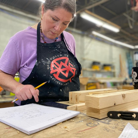 A student laying out joinery at the workbench